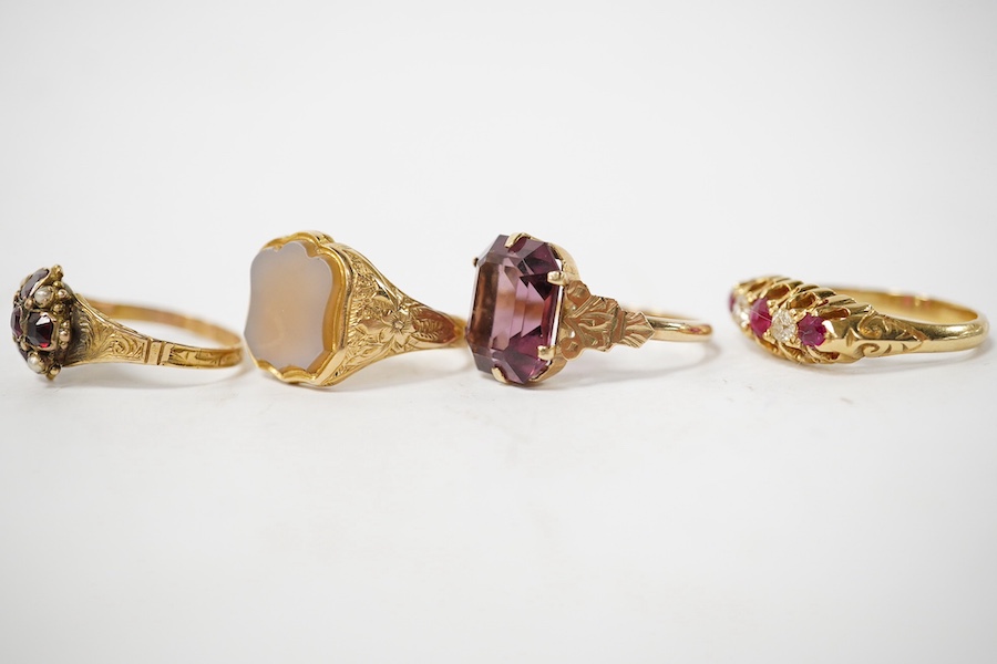 A group of four rings, comprising: a chalcedony signet ring with engraved floral shoulders, size L, partial British hallmarks for 15ct gold; a synthetic ruby and diamond five-stone ring, size N, stamped 18CT; a ring set